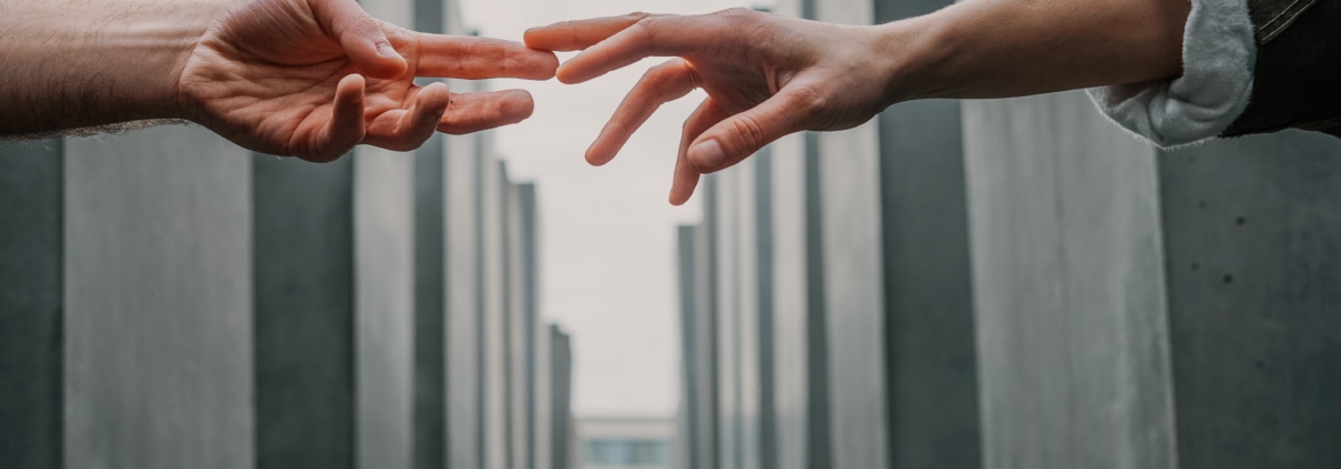 Two hands reaching and touching across buildings