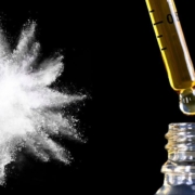 White powder explosion and CBD oil on black background