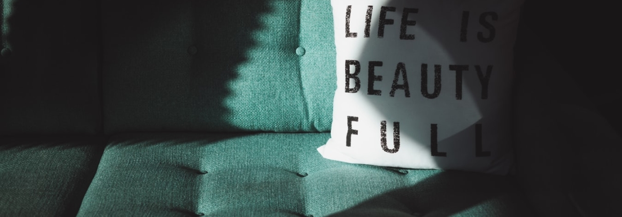 Green sofa with a white pillow holding the text "Life is beautiful"