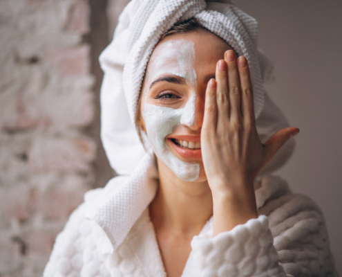 Smiling woman in housecoat having a facemask on one side of her face