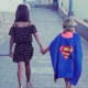 Girl holding hands with child superman