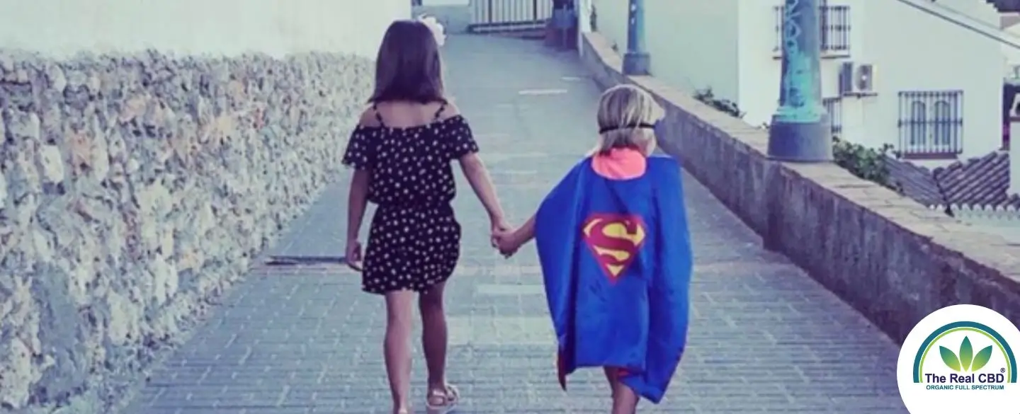 Girl holding hands with child superman