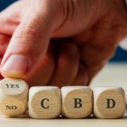 Mann buchstabiert mit der Hand YES CBD in Holzwürfeln