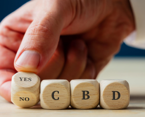 Mann buchstabiert mit der Hand YES CBD in Holzwürfeln