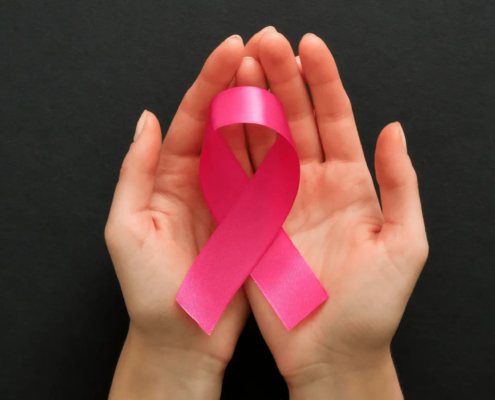 Hand holding a pink cancer ribbon