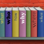 Shelf on red brick wall with line-up of books with questions as titles