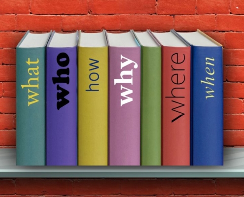 Shelf on red brick wall with line-up of books with questions as titles