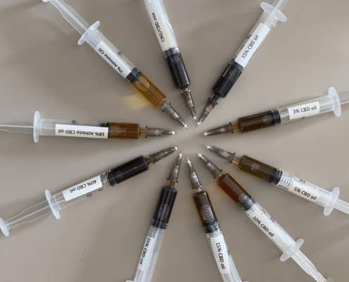 10 seringues contenant différentes huiles de CBD disposées en cercle, montrant la différence de couleur.