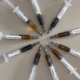 10 syringes with different CBD oil laid out in a circle, demonstrating the colour difference