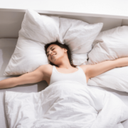 Smiling woman waking up in a bed with white bedsheets