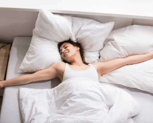 Smiling woman waking up in a bed with white bedsheets