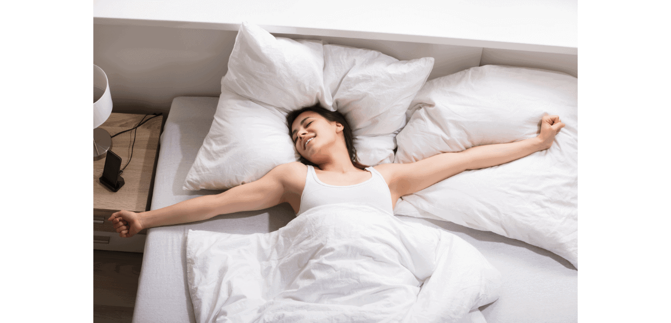 Smiling woman waking up in a bed with white bedsheets