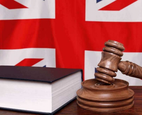 Judge's hammer and a law book in front of the British flag