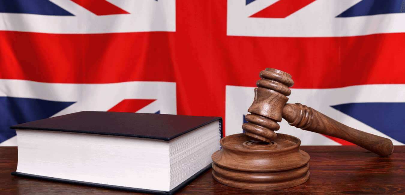 Judge's hammer and a law book in front of the British flag