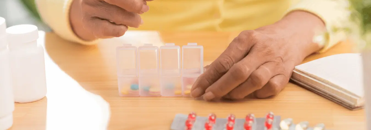 Hands putting pills in to pill organiser