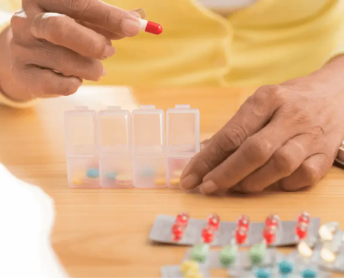 Les mains mettent les pilules dans le pilulier