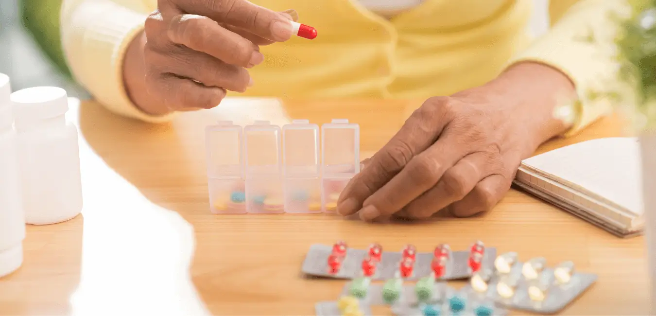 Les mains mettent les pilules dans le pilulier