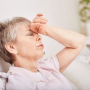 Femme aux yeux fermés se tenant le front en signe de douleur