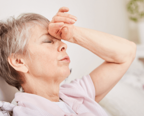 Femme aux yeux fermés se tenant le front en signe de douleur