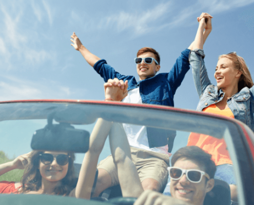 A group of young people driving in a cabriolet having a good time