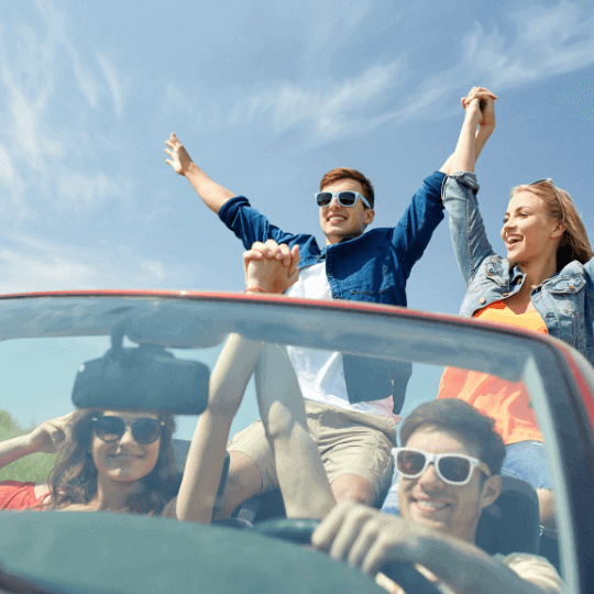 A group of young people driving in a cabriolet having a good time