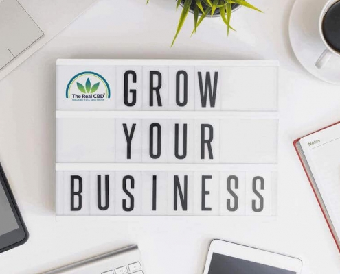 Office table with computer, phone coffee cup, notebook and a sign saying "Grow your business"