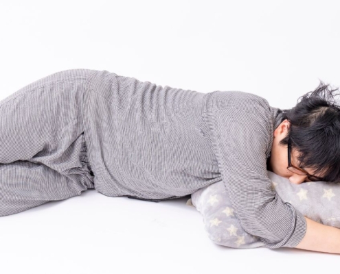 Person sleeping on the floor in grey pyjamas