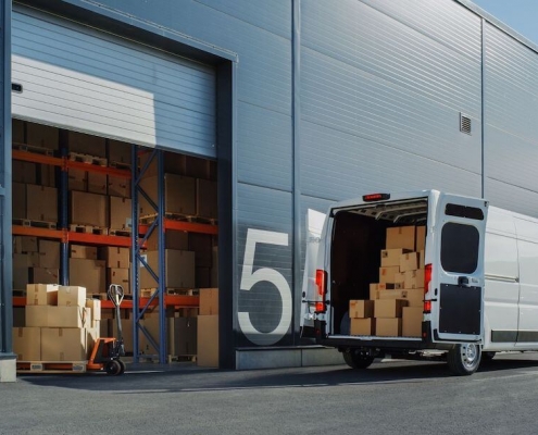 Camionnette blanche aux portes ouvertes devant un entrepôt