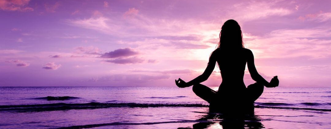 Femme en position de yoga au bord de la mer