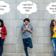 Teenagers on their smartphones up against a brick wall