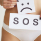 Woman holding SOS sign over her pelvis