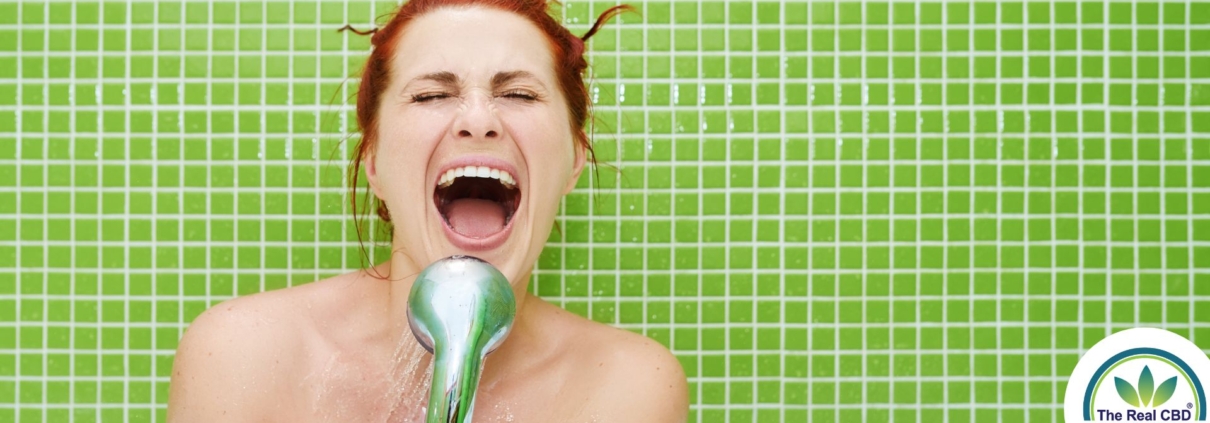 Happy woman singing into the shower head