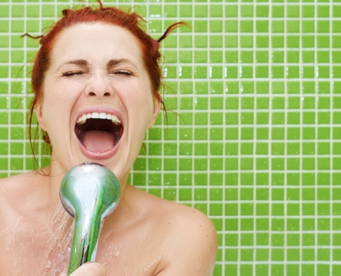 Femme heureuse chantant dans la pomme de douche