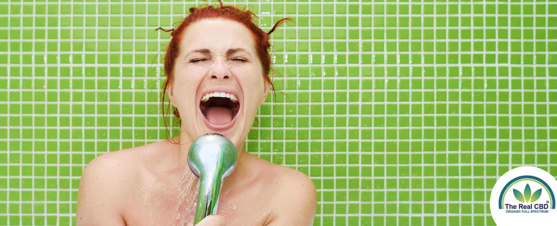 Happy woman singing into the shower head