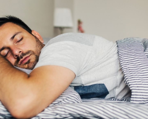 Homme dormant profondément sur le ventre dans un lit neuf