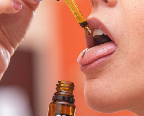 Woman taking CBD oil on the tongue