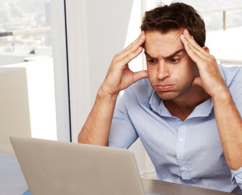 Homme regardant avec frustration l'écran d'un ordinateur portable