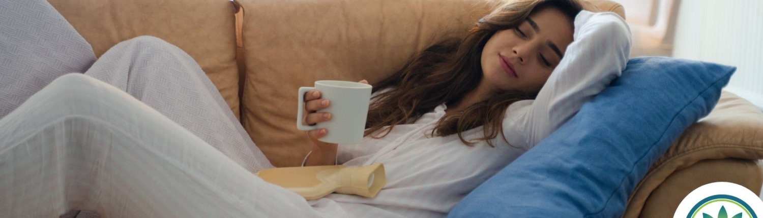 Woman laying on a sofa drinking from a white mug