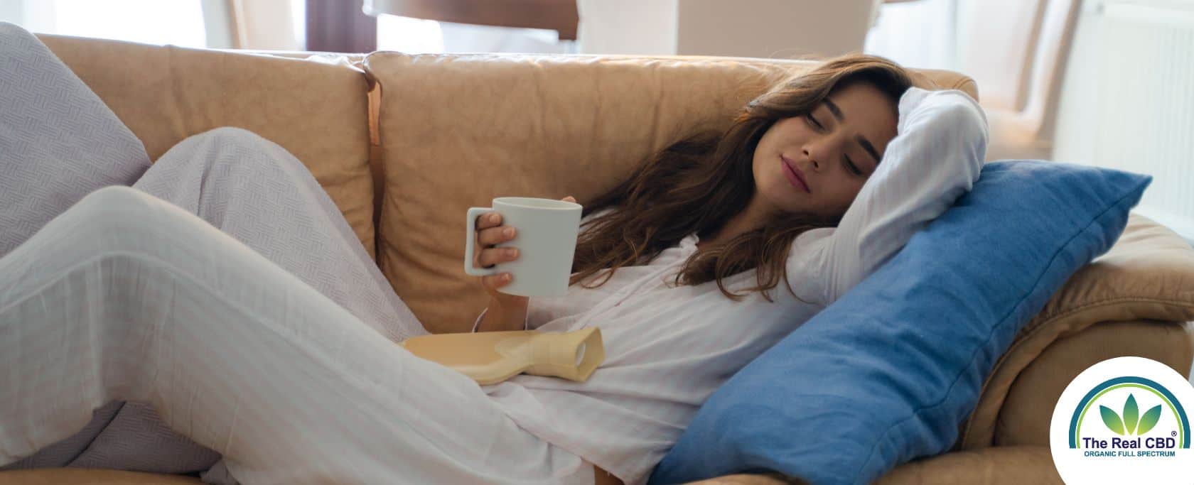 Woman laying on a sofa drinking from a white mug