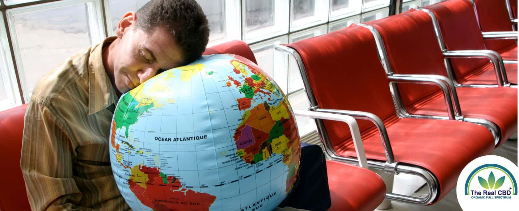 Man sleeping with his head on a globe in an airport