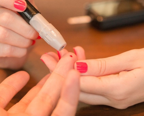 Frau macht einen Diabetes-Fingerstich bei einem Mann