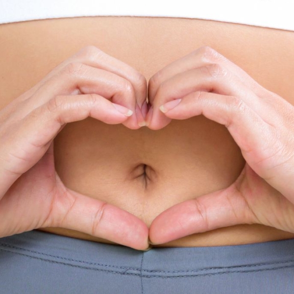 Woman making heart shape with her hands in front of her bellybutton