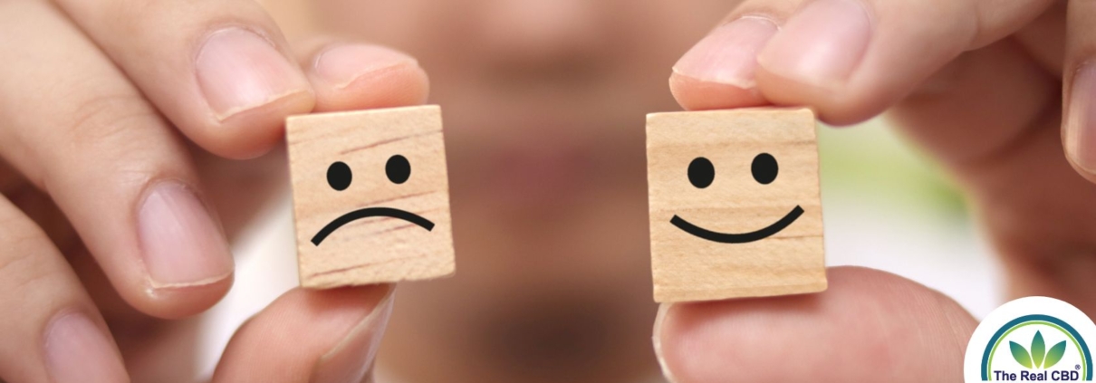 Hands holding happy and sad faced wooden cubes