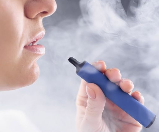 Person vaping on a blue vapepen blowing smoke