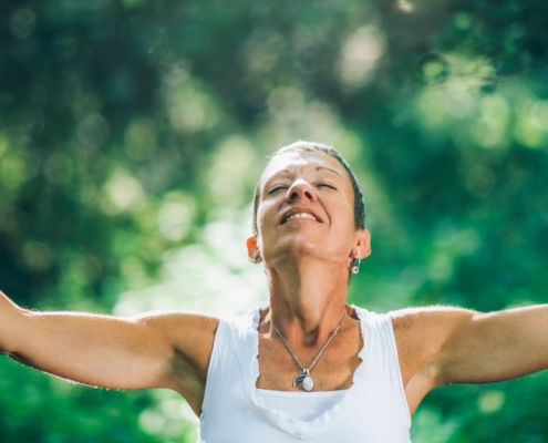 Femme heureuse ouvrant les bras dans une forêt