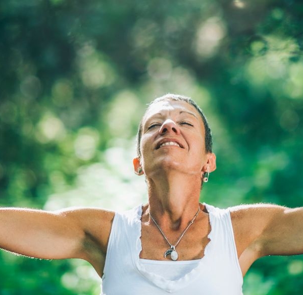 Happy woman opening her arms in a forest