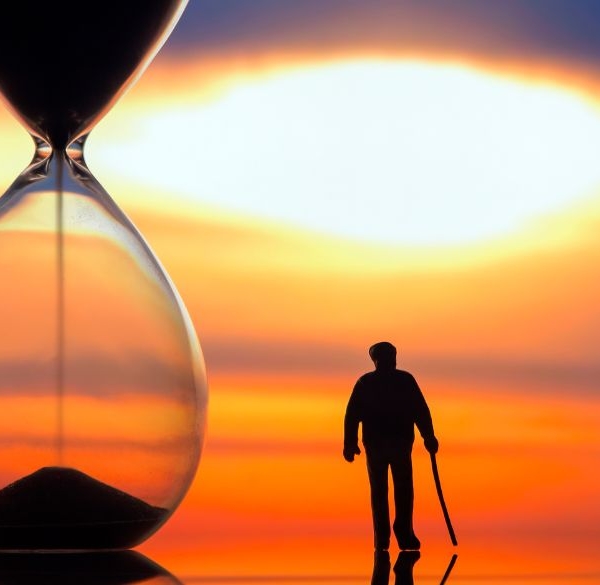 Old man walking next to a time glass