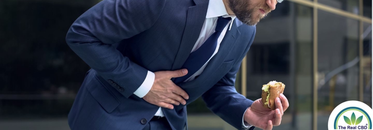 Man with food in hand bending over in pain