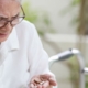 Elderly person looking confused at tablets in hand