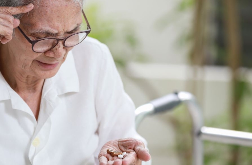 Elderly person looking confused at tablets in hand